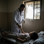 Profissional de saúde em Gaza cuidando de paciente ferido.