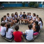 Alunos em sala de aula sorrindo e interagindo.